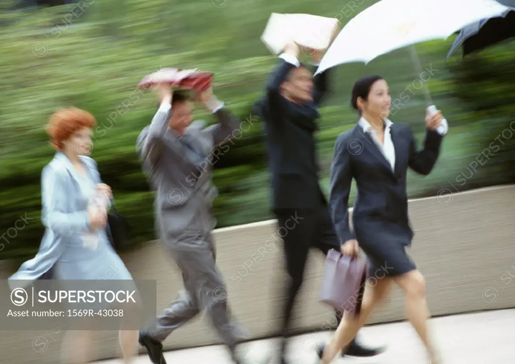 Group of business people running in rain, blurred