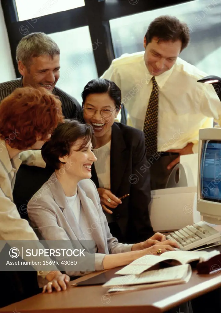 Five businesspeople gathered around desk, smiling