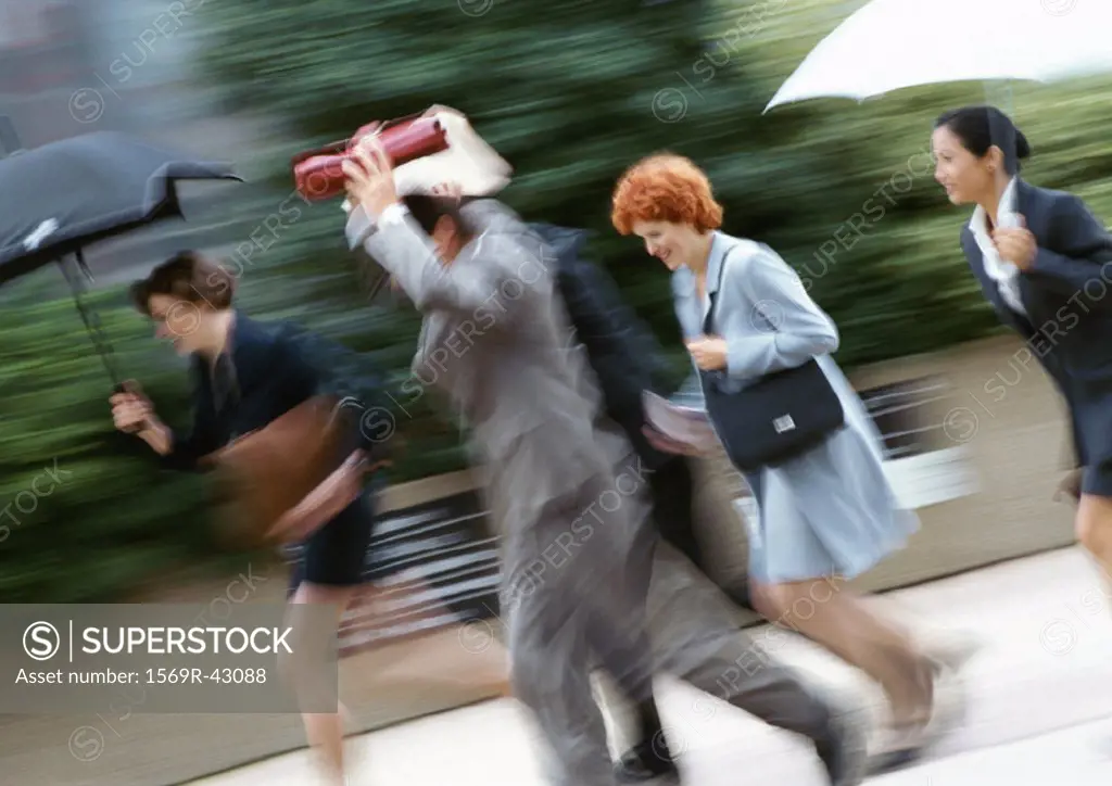 Businesspeople running in rain, blurred