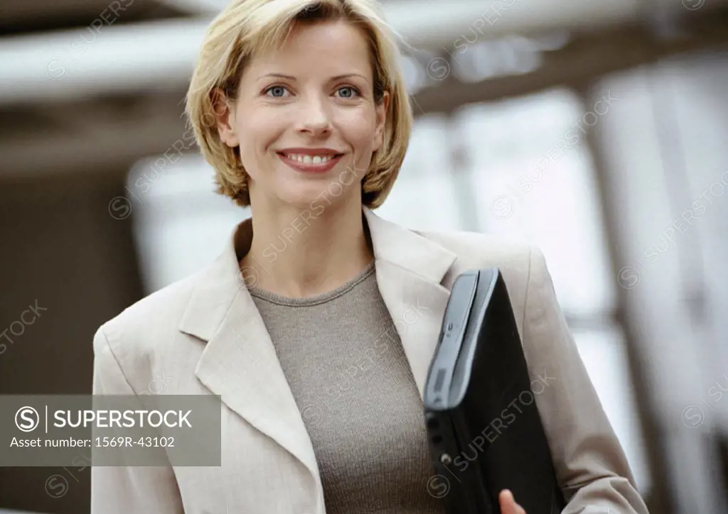 Businesswoman holding laptop computer, smiling at camera, portrait