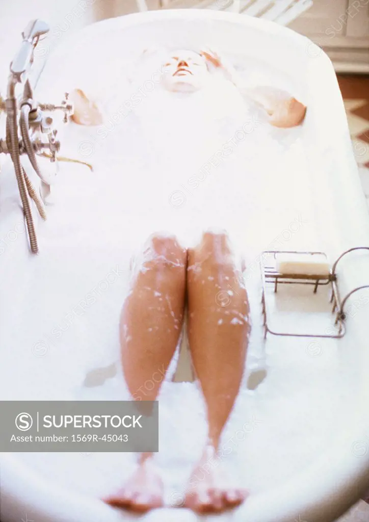 Woman taking bubble bath, high angle view, blurred