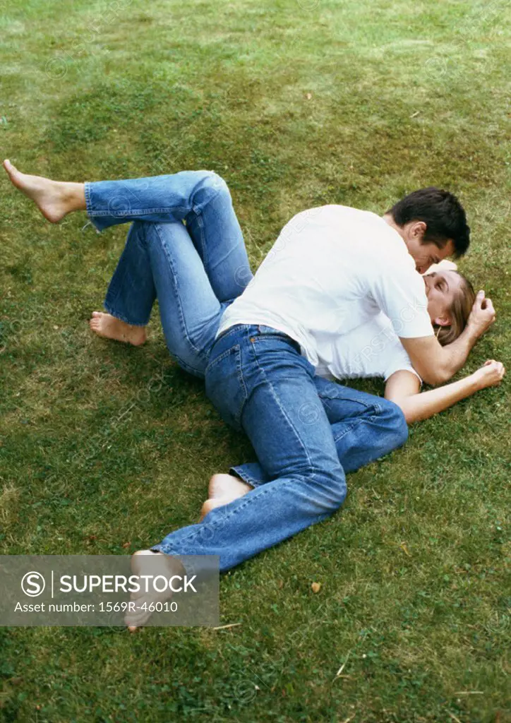 Couple lying on grass, man leaning over woman