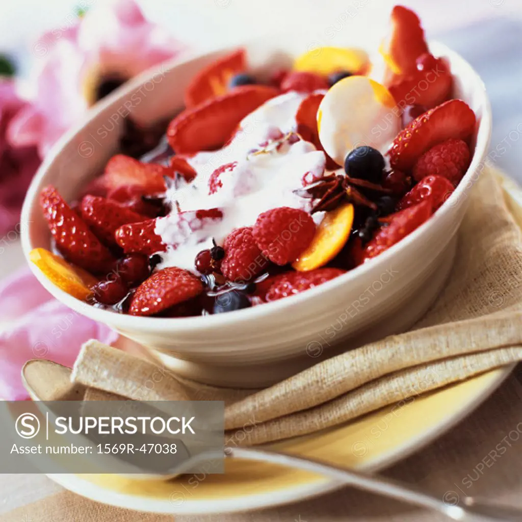 Bowl of summer fruits with cream and spices, close-up