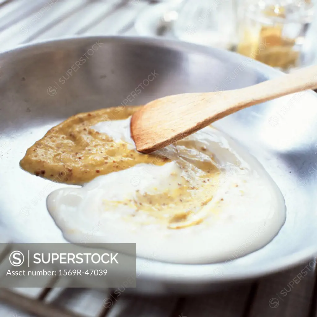 Wooden spoon stirring sauce, close-up