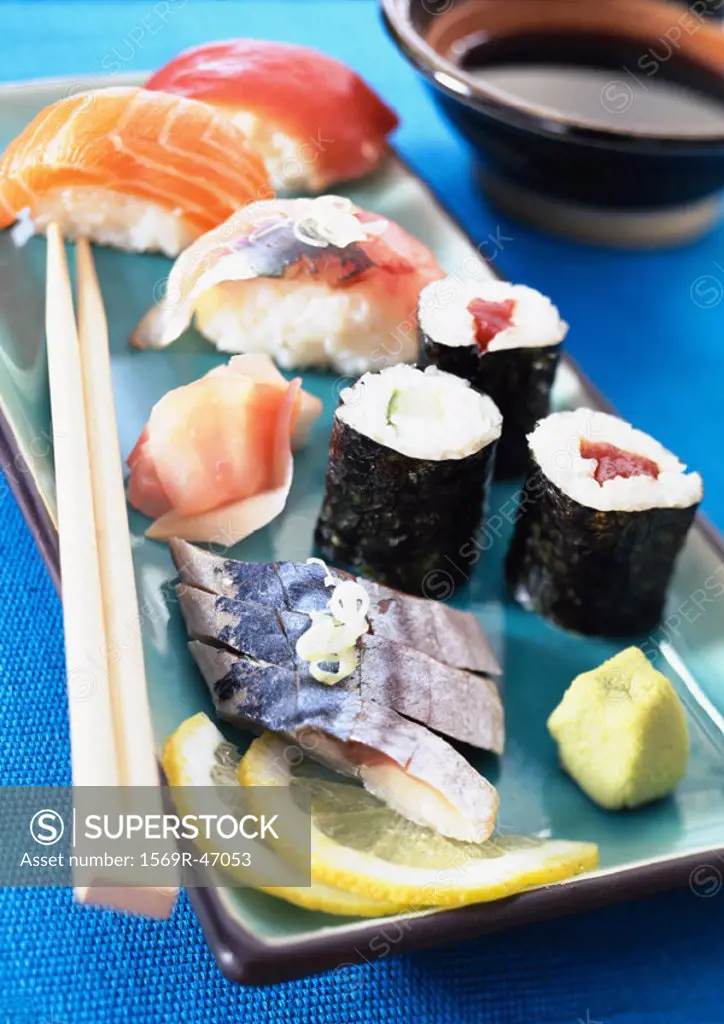 Various types of sushi on plate with chopsticks, close-up