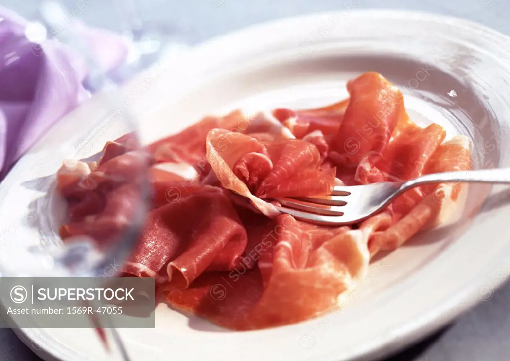 Plate of Parma ham with fork, close-up