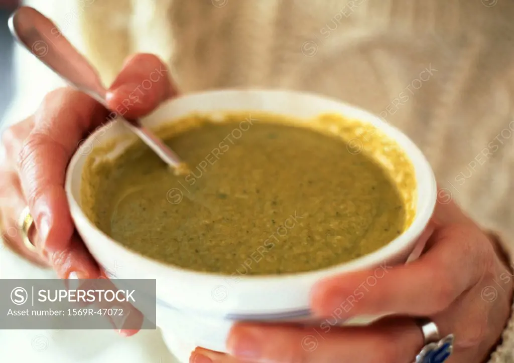 Hands holding bowl of leek soup, close-up