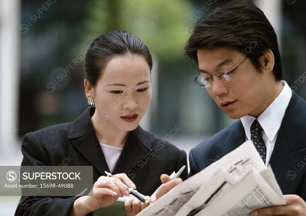 Man and woman looking at newspaper