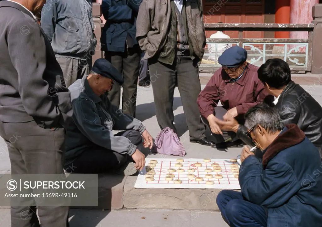 China, Xinjiang Province, Urumqi, group of people playing mah-jong on ground