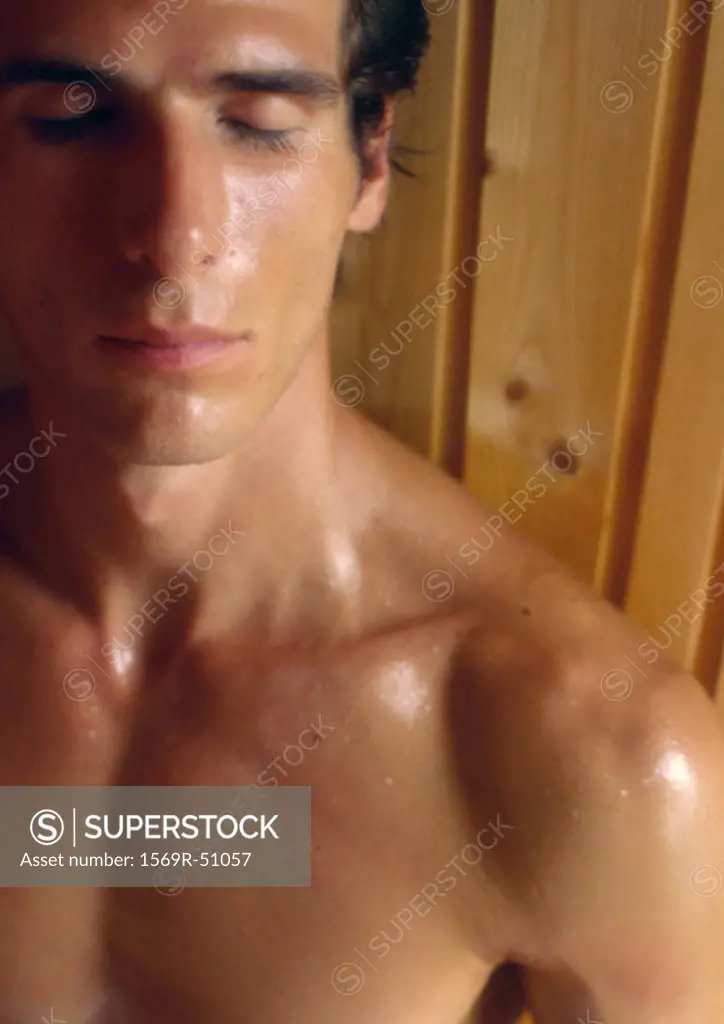 Bare-chested man in sauna with eyes closed, close-up