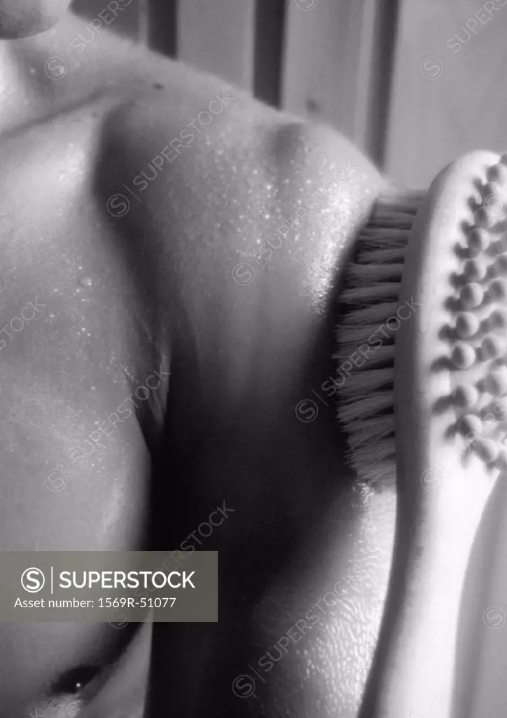 Brush on bare shoulder in sauna, close-up, b&w