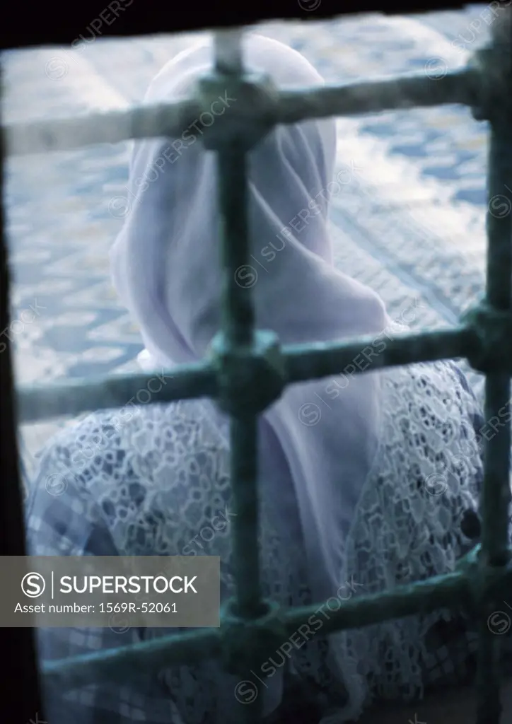 Israel, woman wearing headscarf standing behind behind window, rear view