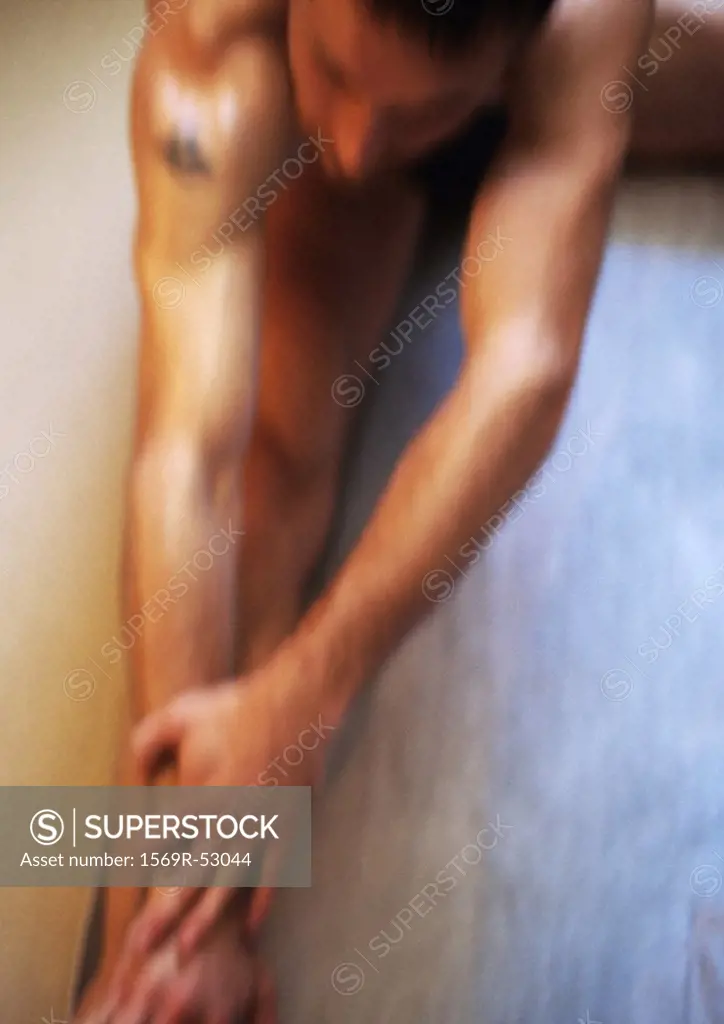 Nude man stretching, high angle view, blurred