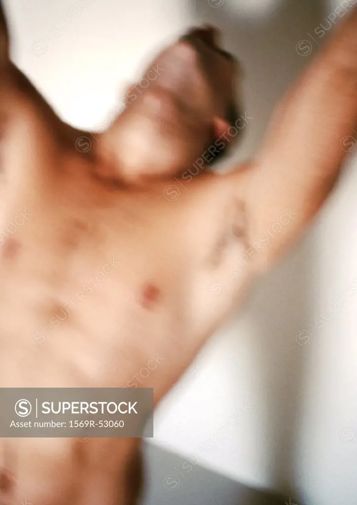 Bare-chested man raising arms, blurred