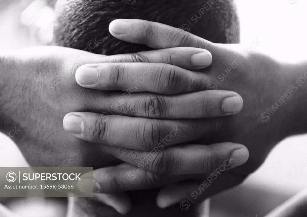 Man´s hands clasped behind head, close-up, b&w