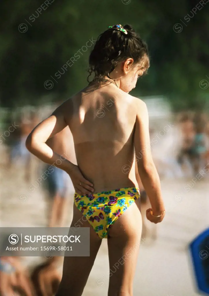 Bare-chested girl on beach, rear view