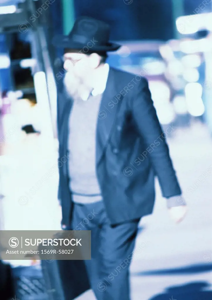 Mature man holding briefcase, walking in street