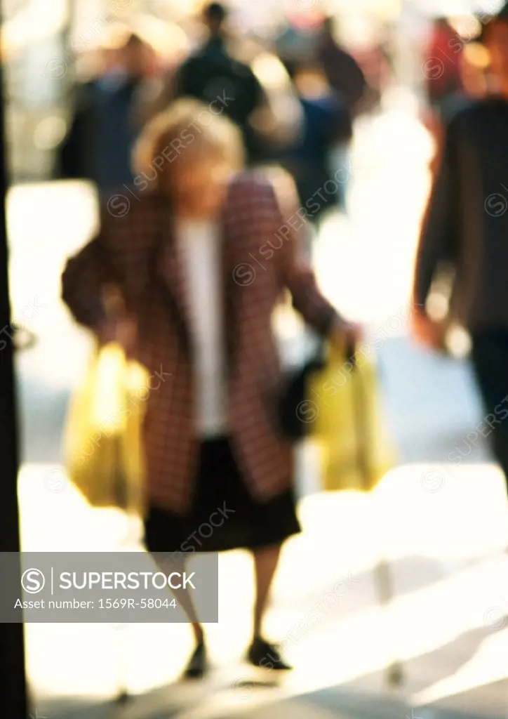 Woman carrying bags in street, blurred