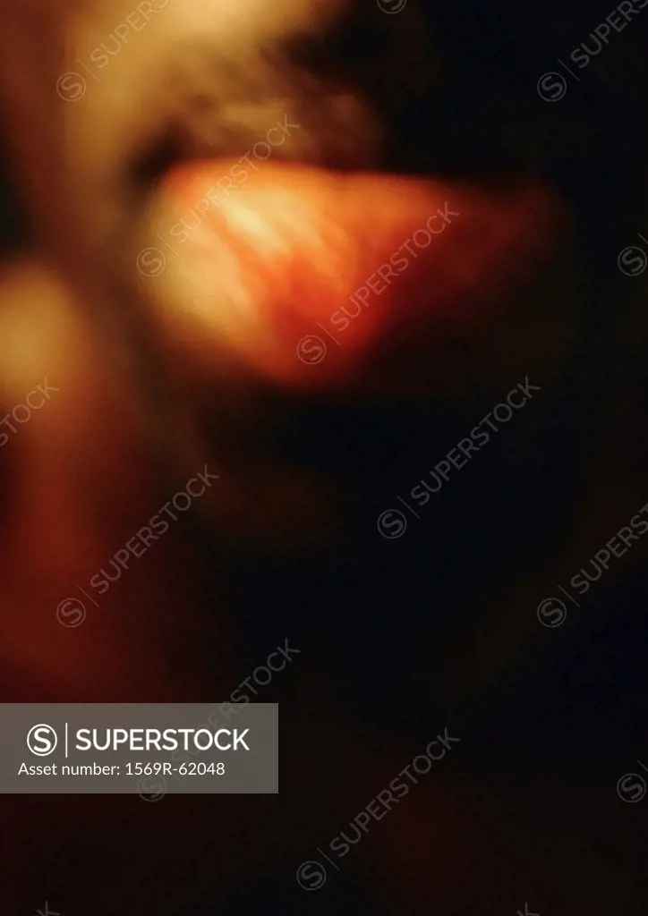 Man sticking tongue out, close up, blurred
