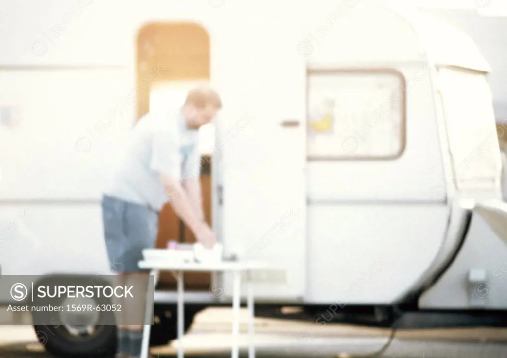 Man standing in front of camper, blurred