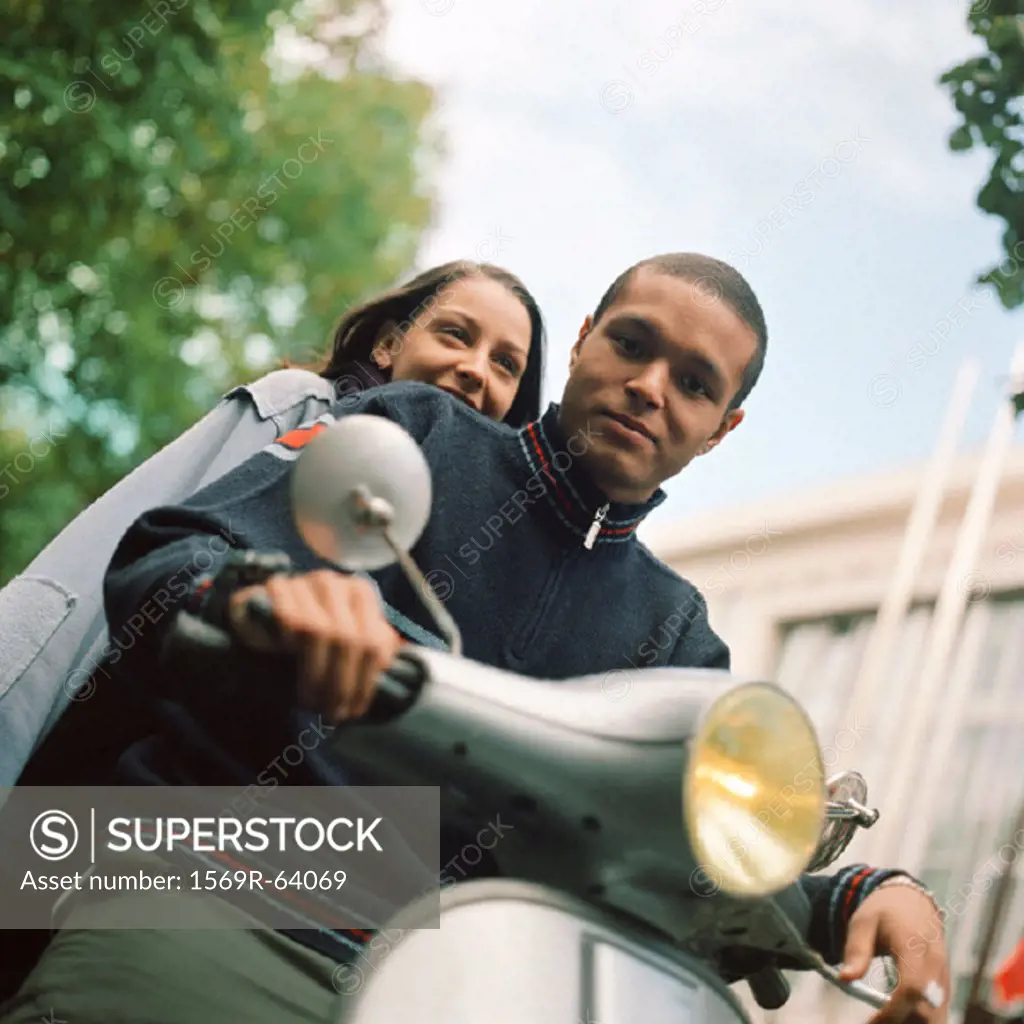 Young man and young woman on motor scooter, waist up, tilt