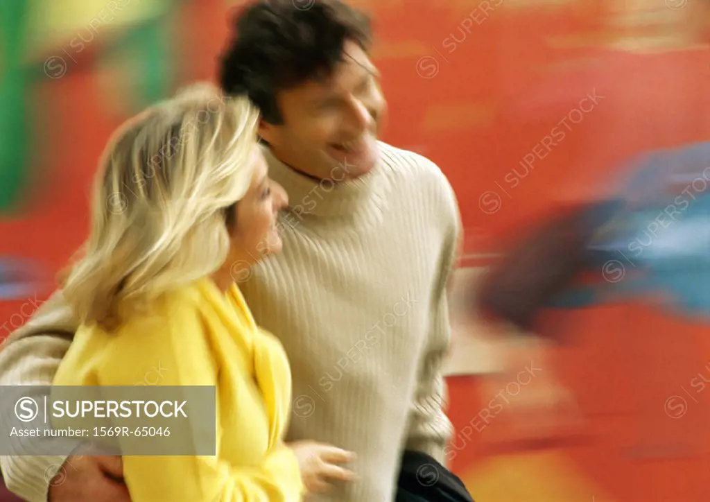 Man and woman walking together, man´s arm around woman, blurred