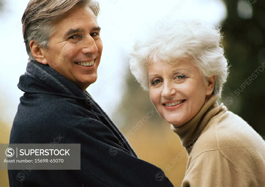Man and woman smiling over shoulders into camera, close-up