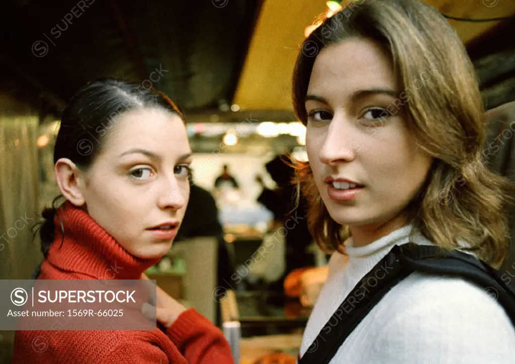 Two young women in store, looking at camera, head and shoulders, close-up