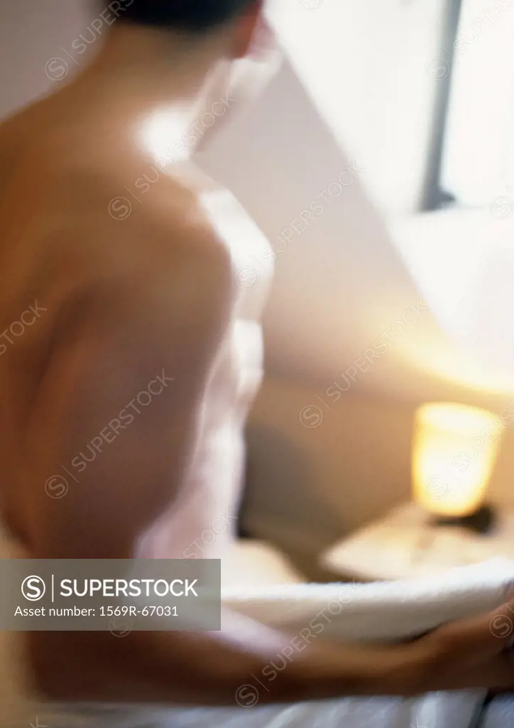 Man wrapping towel around waist, partial view, blurred