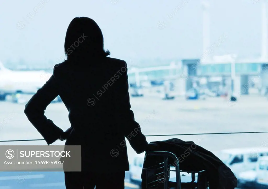Businesswoman next to luggage, silhouette, airplanes in background