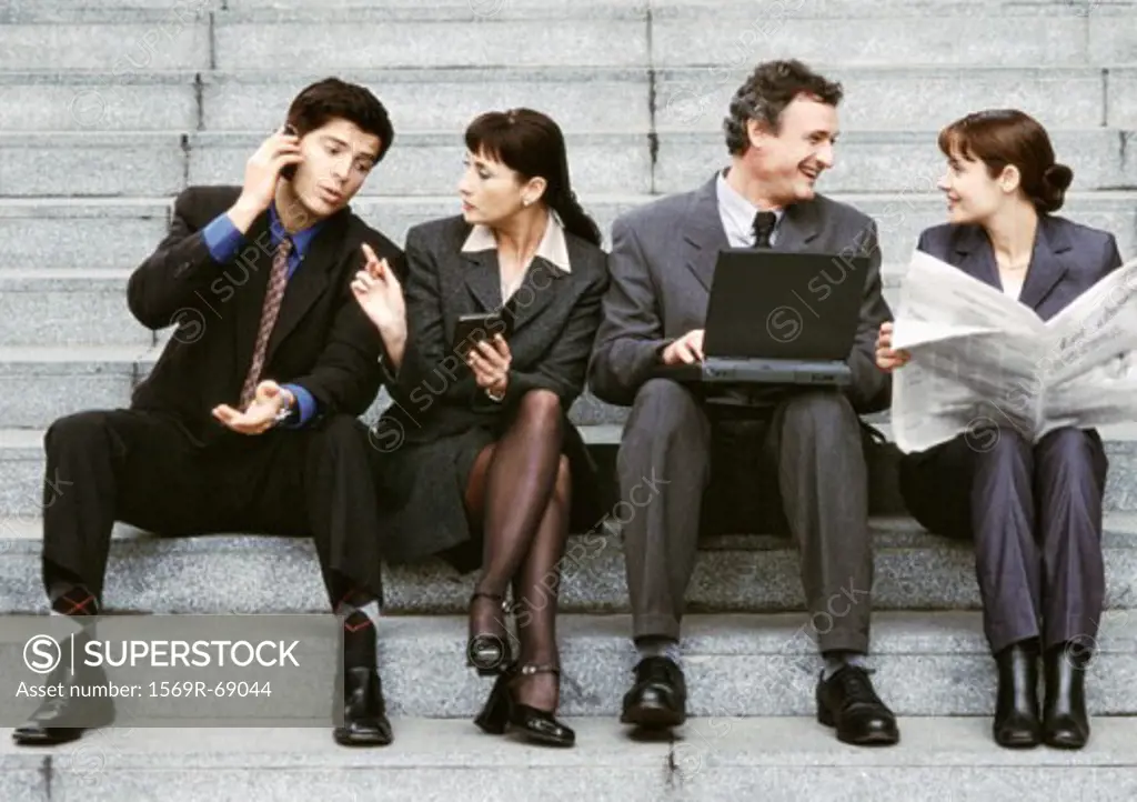 Four business people sitting on steps, interacting
