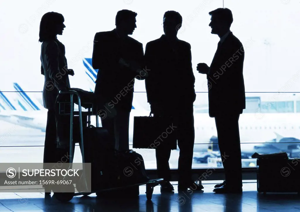 Group of business people standing inside airport, silhouette