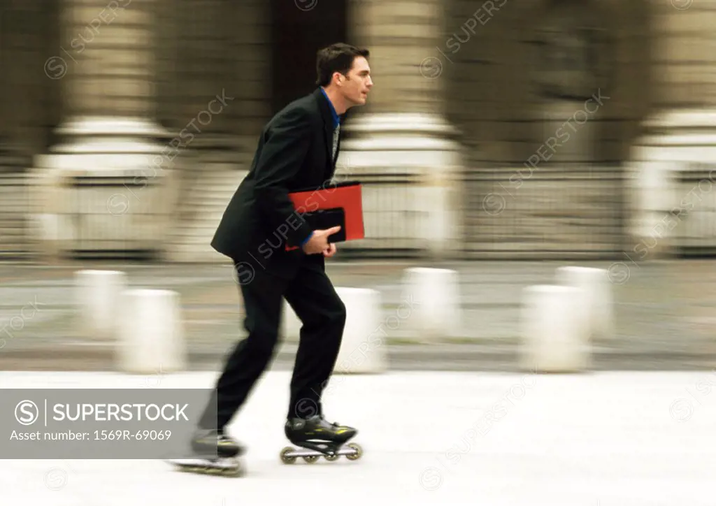 Businessman rollerblading in front of building, blurred
