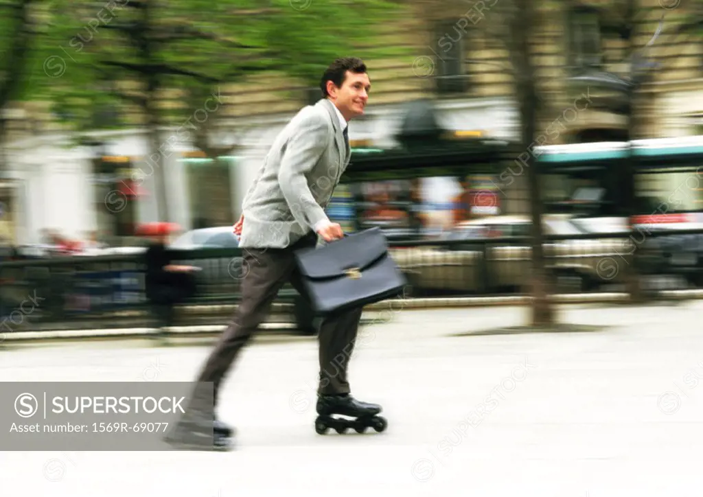 Businessman rollerblading in park, blurred