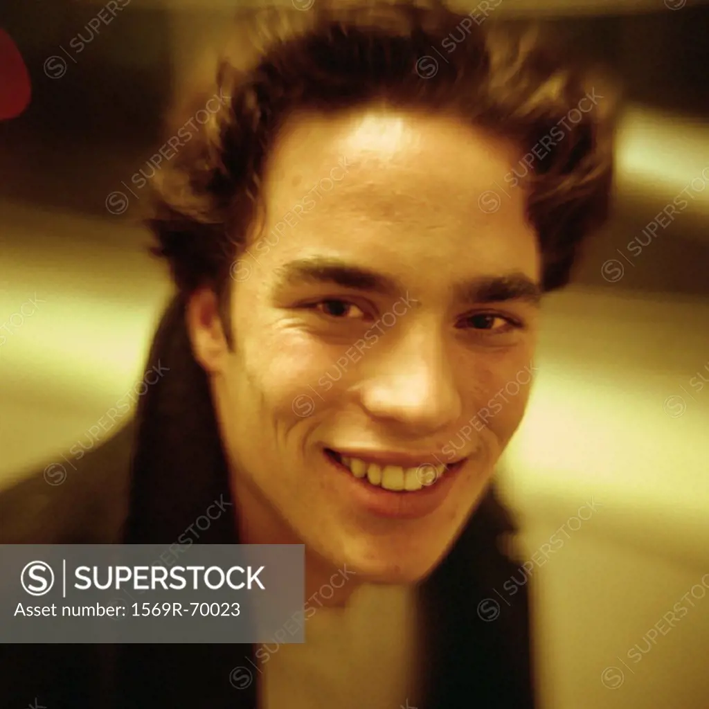 Young man smiling at camera, close-up, portrait