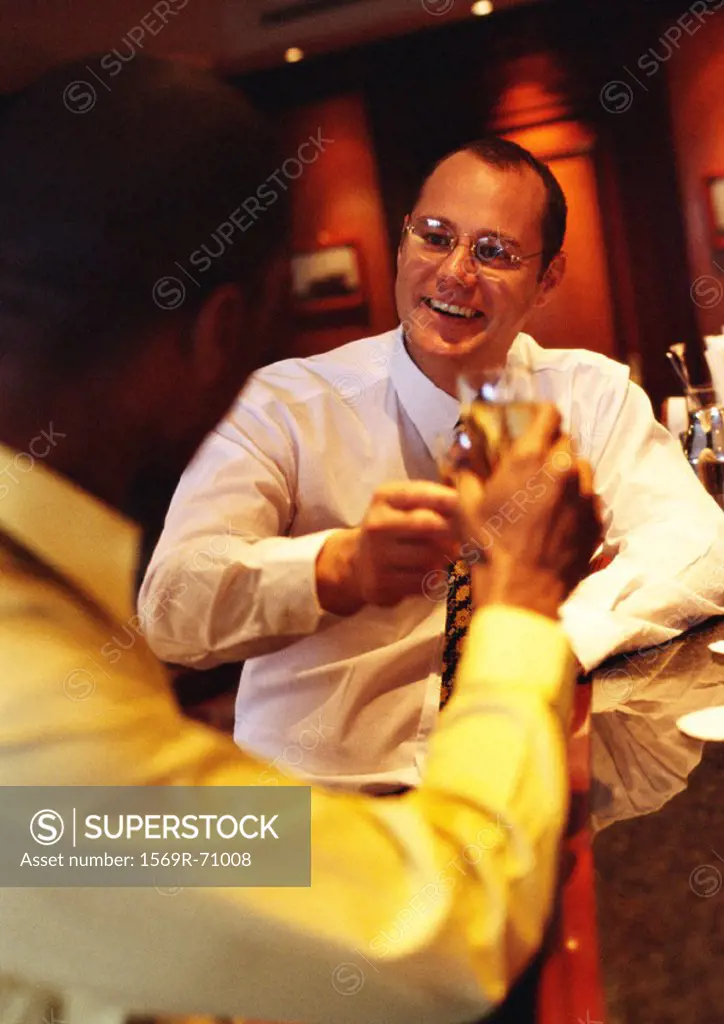 Businessmen raising glasses at bar