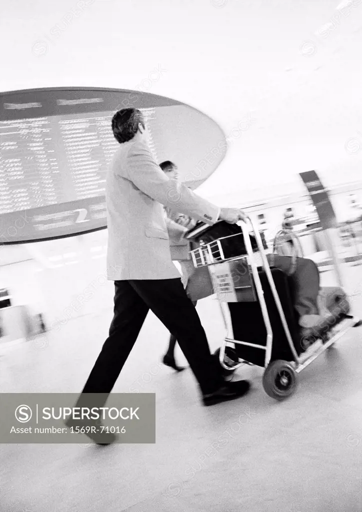 Businessman walking through terminal, blurred b&w