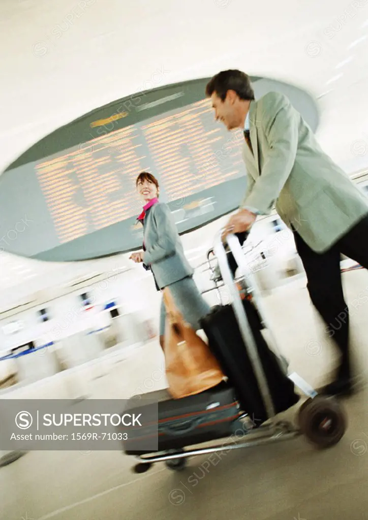 Businessman and businesswoman walking through airport terminal, blurred