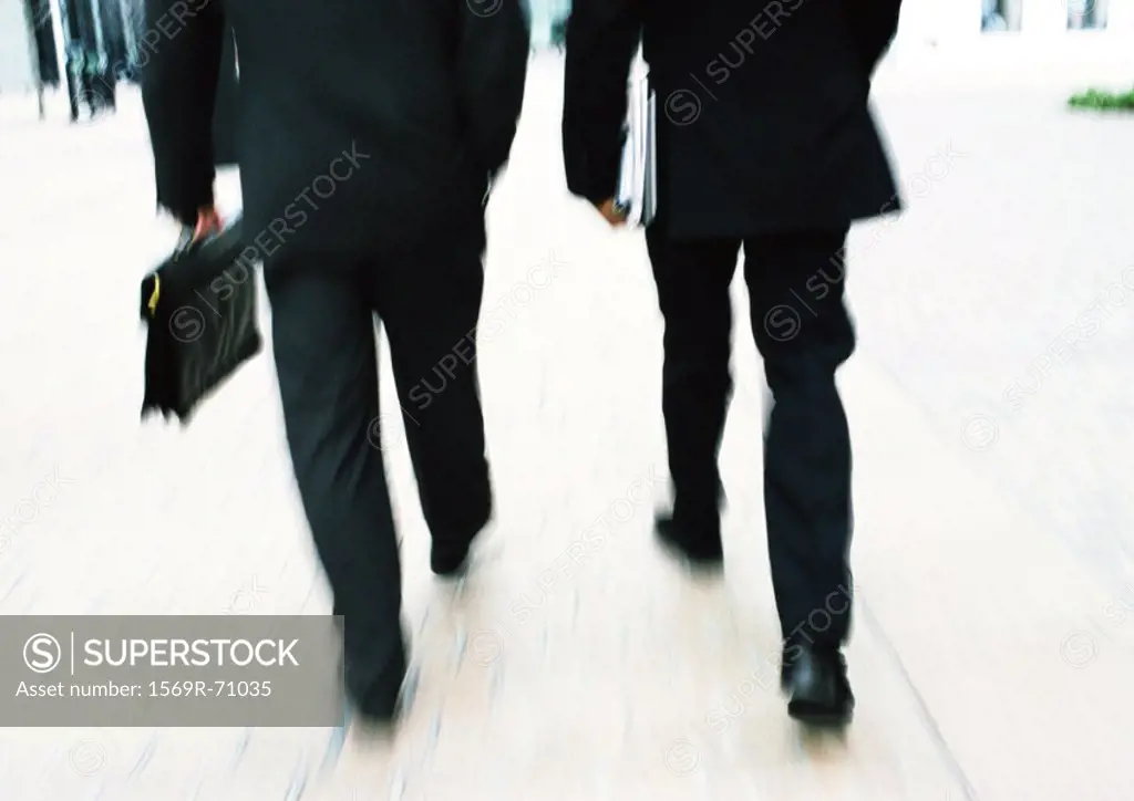 Businessmen walking together, lower section, blurred