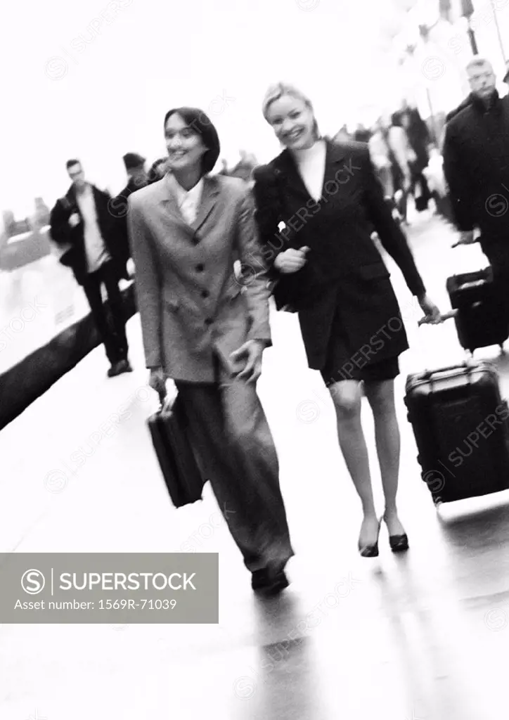 Businesswomen walking together on platform, blurred, b&w