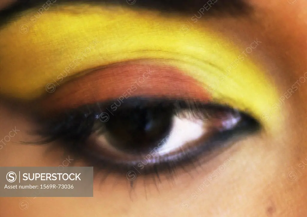 Woman´s brown eye, yellow eye make up, blurred close up