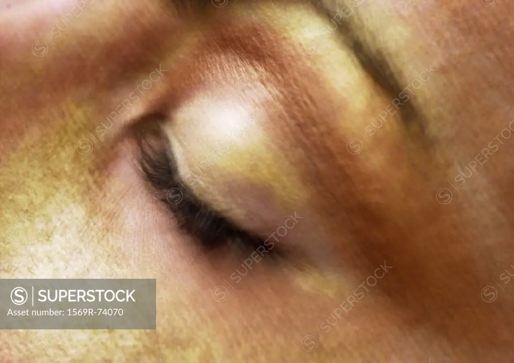 Woman´s closed eye, gold make-up on face, close-up, blurry