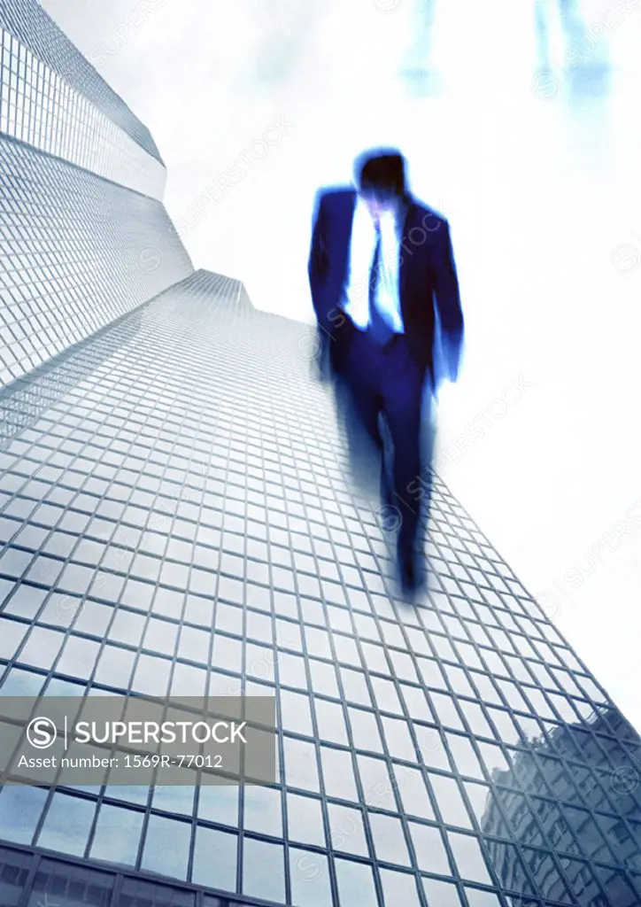 Businessman walking on side of skyscraper, montage