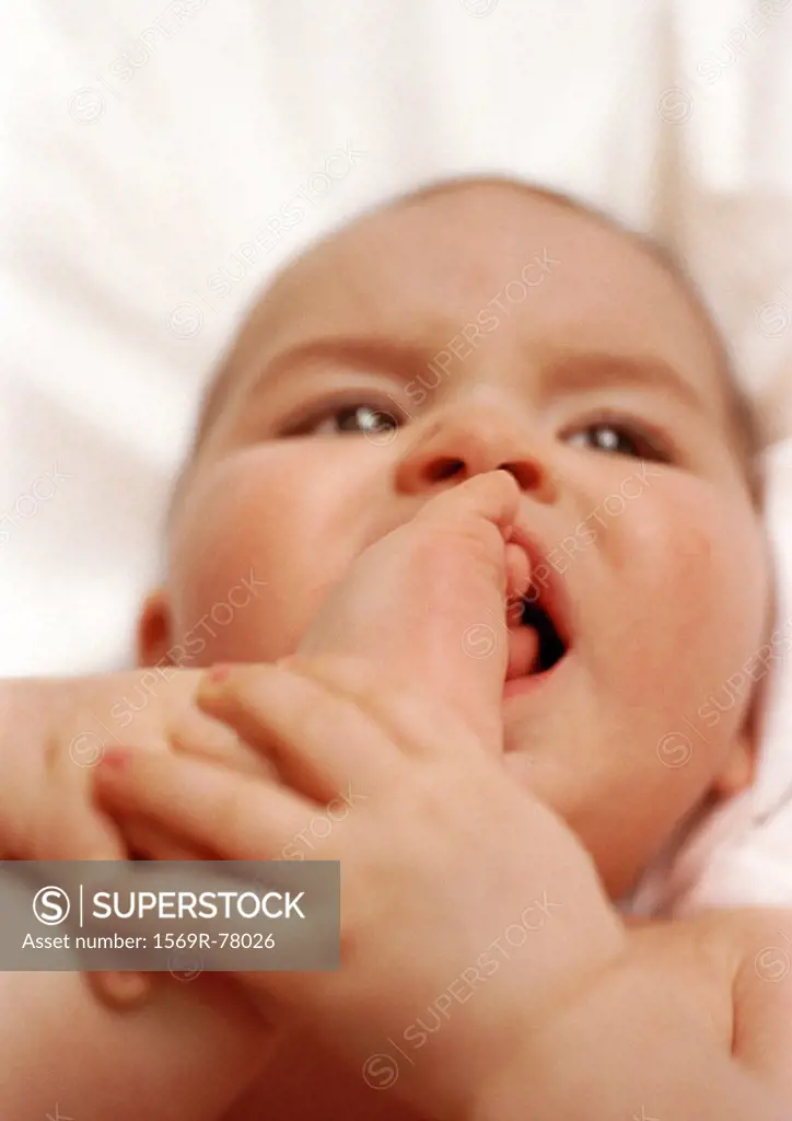 Baby lying on back, putting foot in mouth, close-up