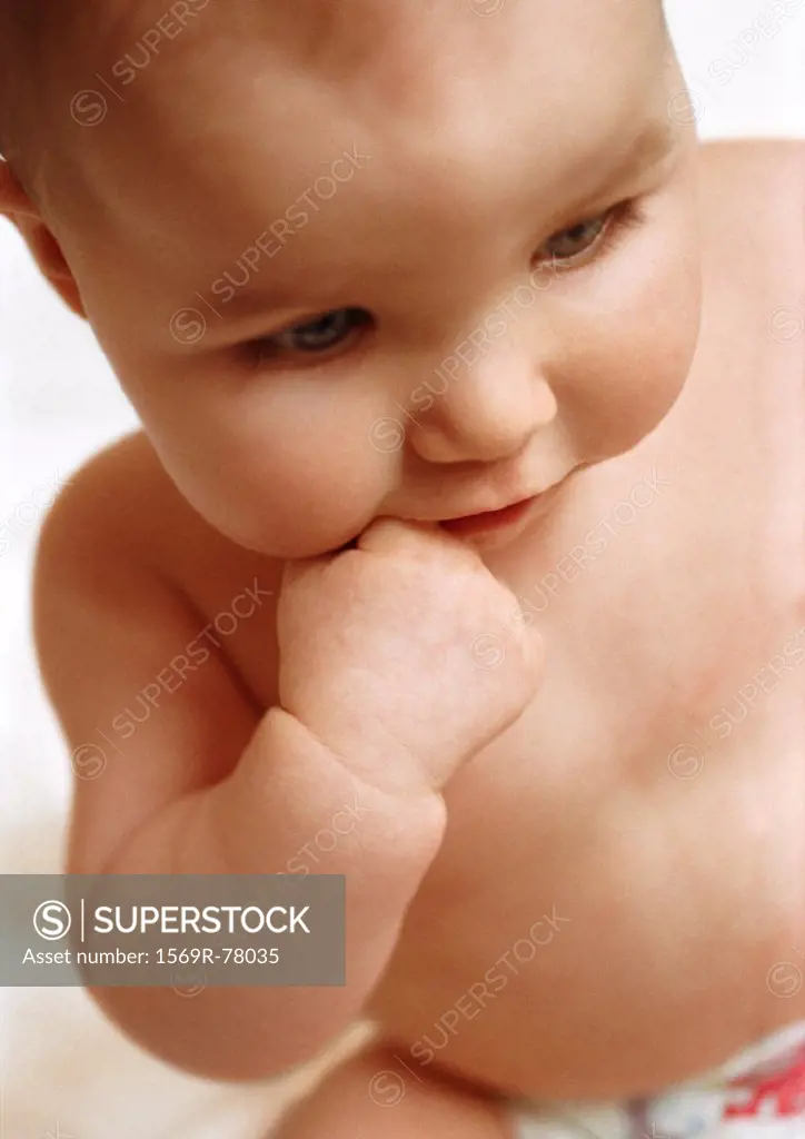 Baby with finger in mouth, looking down, close-up