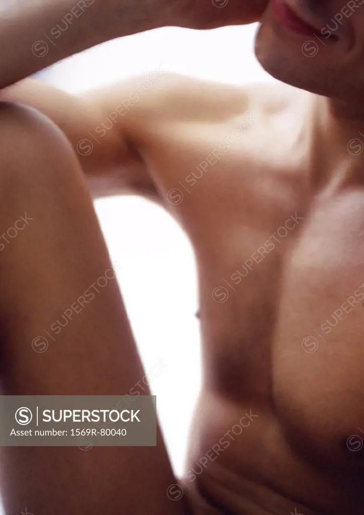 Nude man resting elbow on knee, cropped, close-up