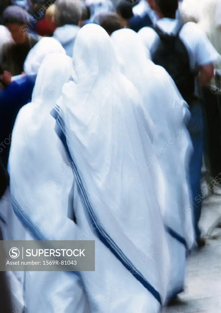 Israel, Jerusalem, nuns clothed in white looking toward crowd, rear view, blurry