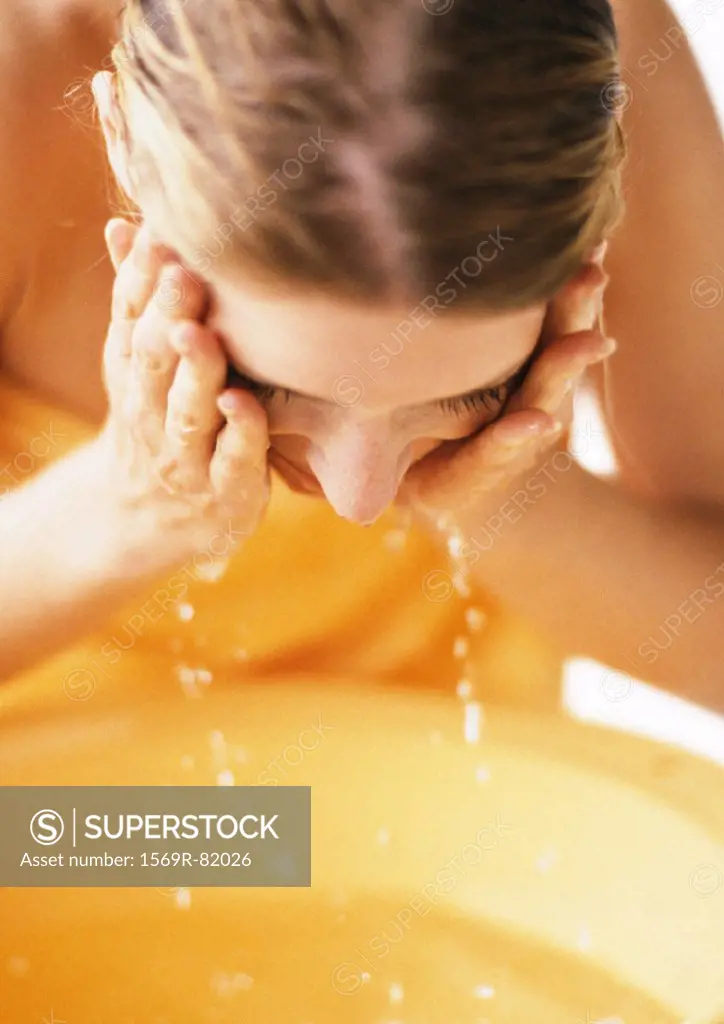 Woman leaning forward, washing face, close-up