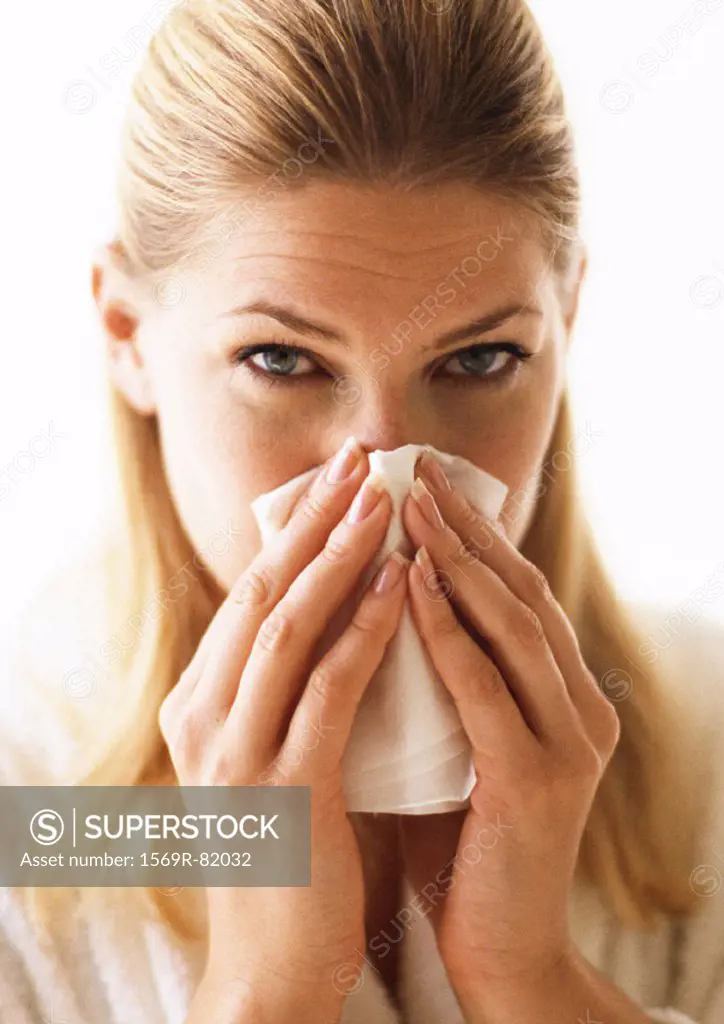Woman blowing nose, close-up