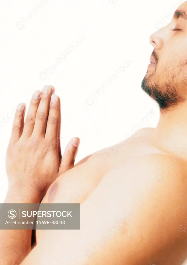 Barechested man praying, side view